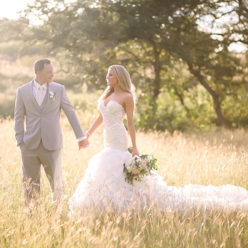 bride and groom hold hands and look at each other
