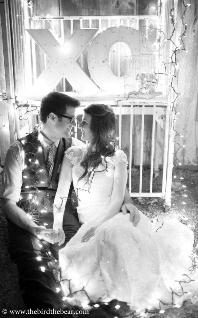 Bride and groom wrapped in christmas lights after their wedding at Three Points Ranch in Dripping Springs, TX.