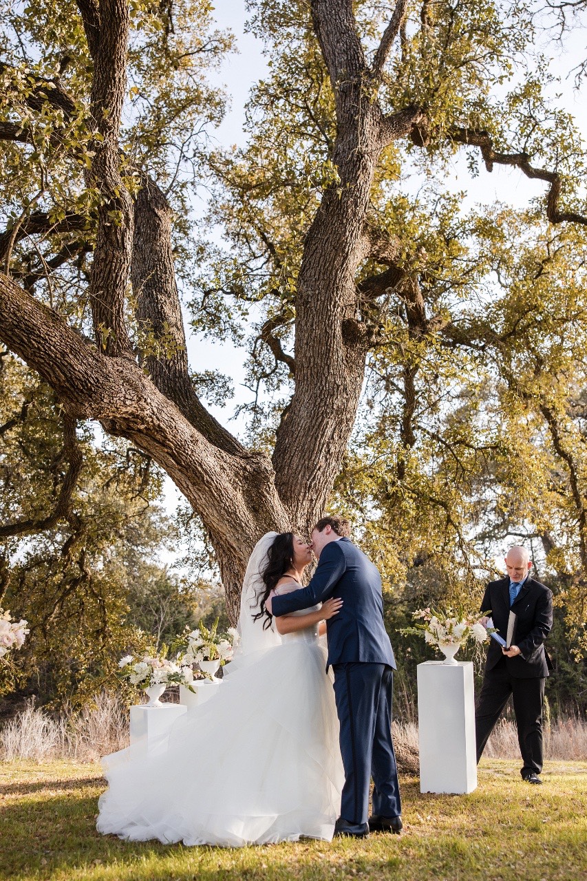 M kissing L's forehead during recessional at Pecan Springs Ranch Austin wedding