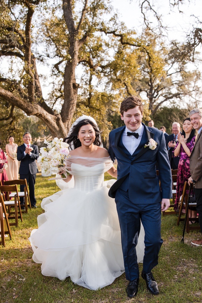 Groomsmen and bridesmaids surrounding couple L and M at Pecan Springs Ranch