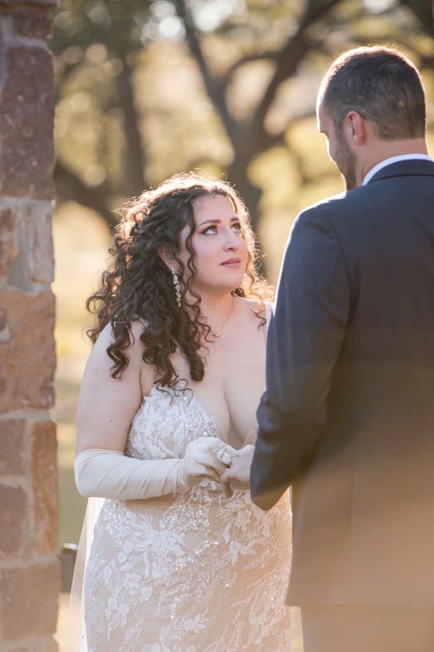 Couple holding hands during vows at fall wedding in Dripping Springs