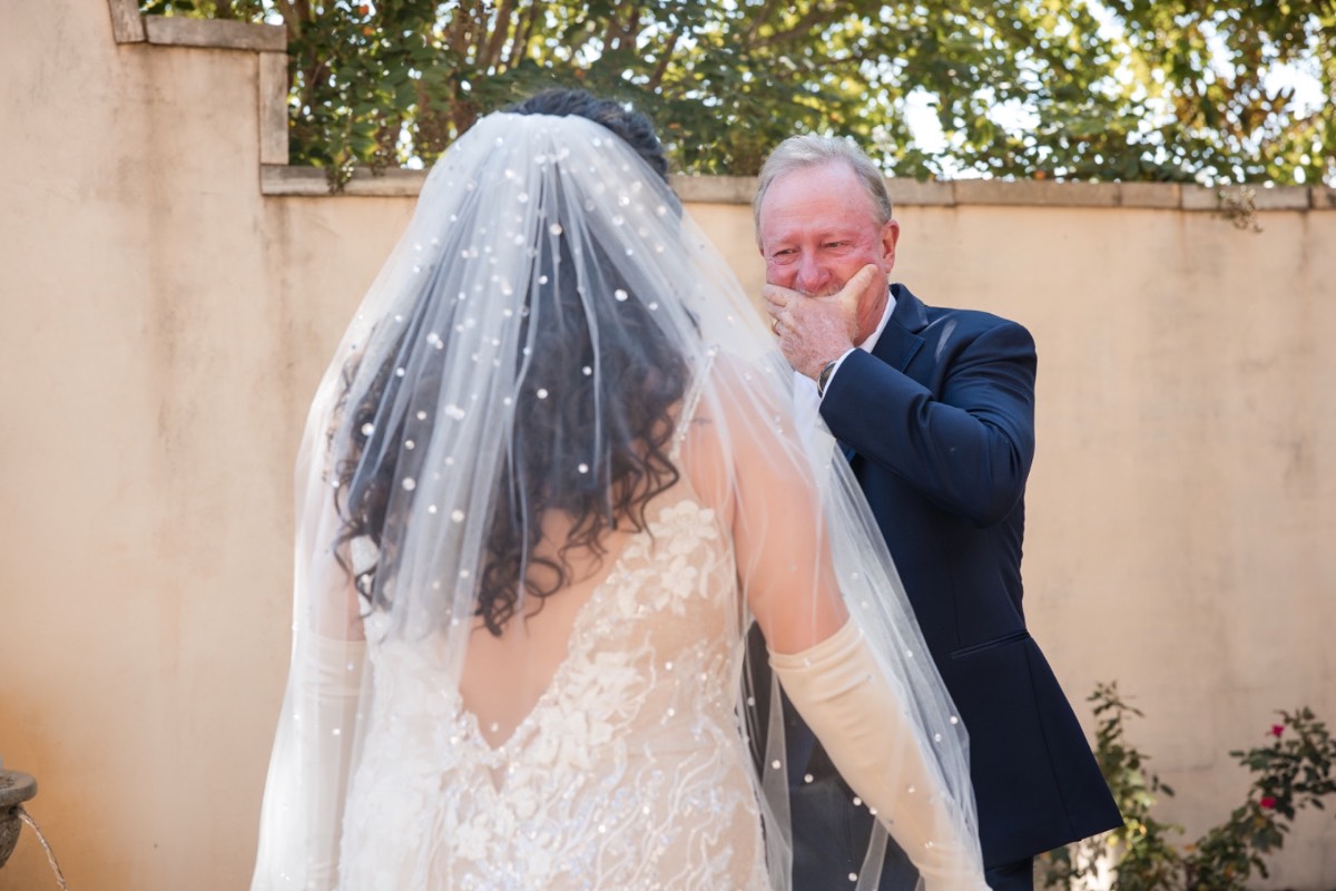 Bridesmaid helping bride into white wedding dress at Ma Maison venue