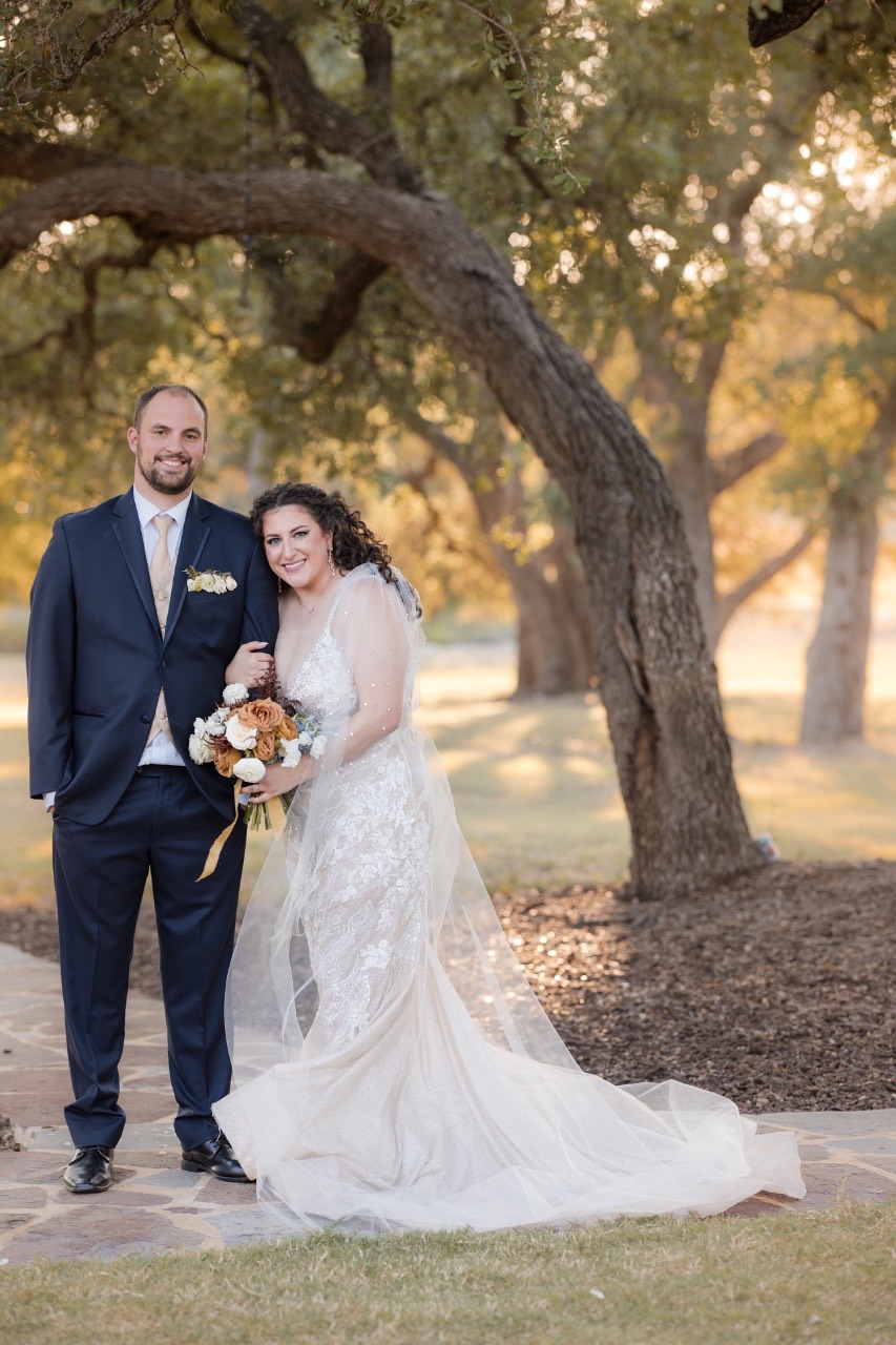 C and C posed against rustic barn backdrop at fall wedding venue