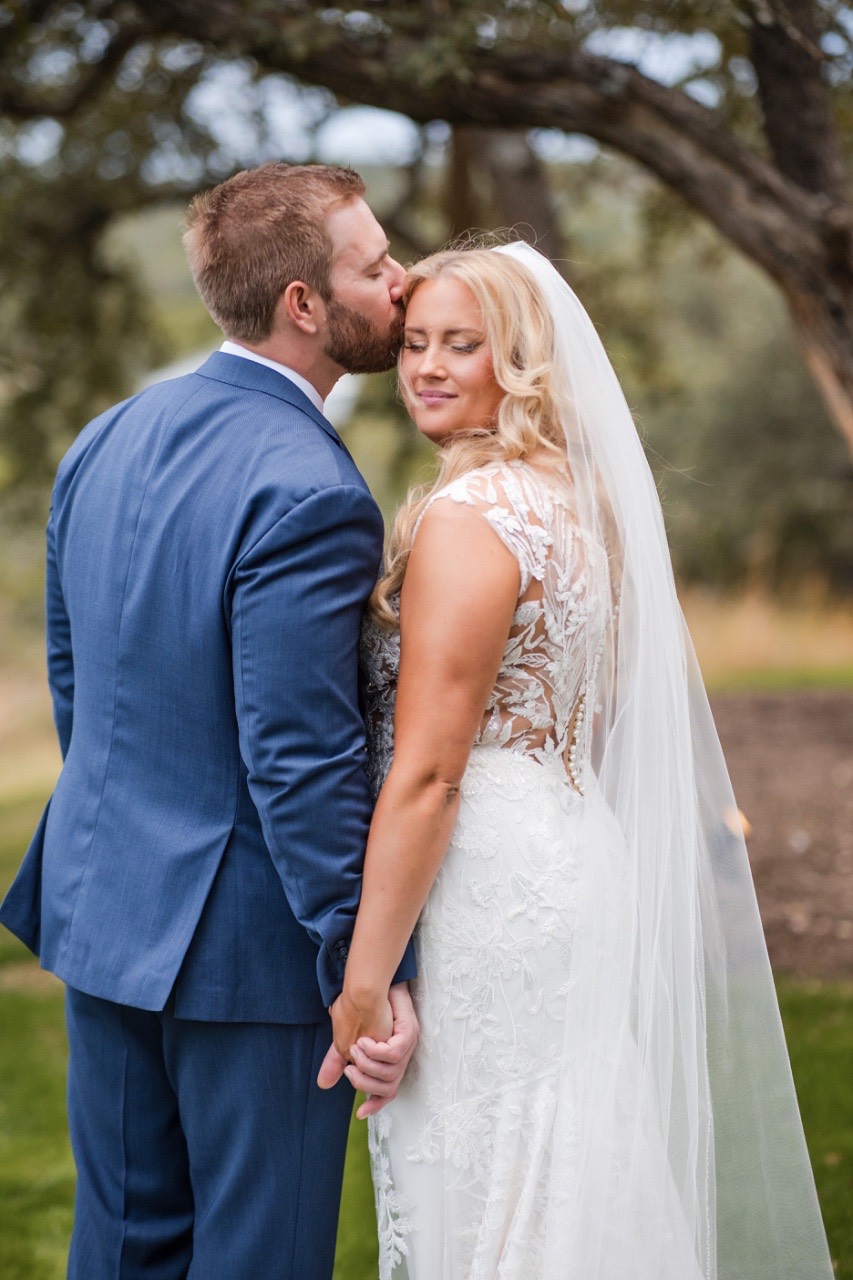 Groom sliding ring onto bride's hand at Canyonwood Ridge venue