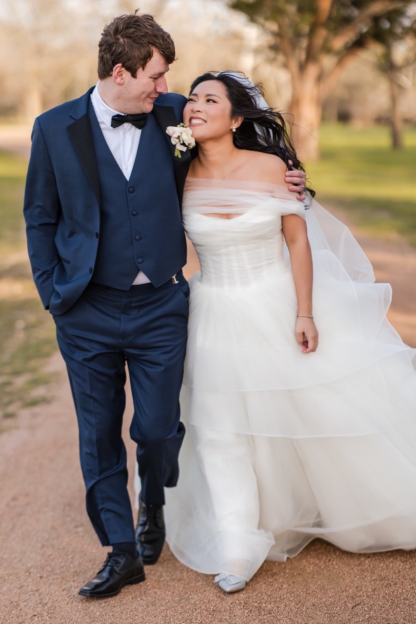 Bride and groom L and M posing near Pecan Springs Ranch landscape