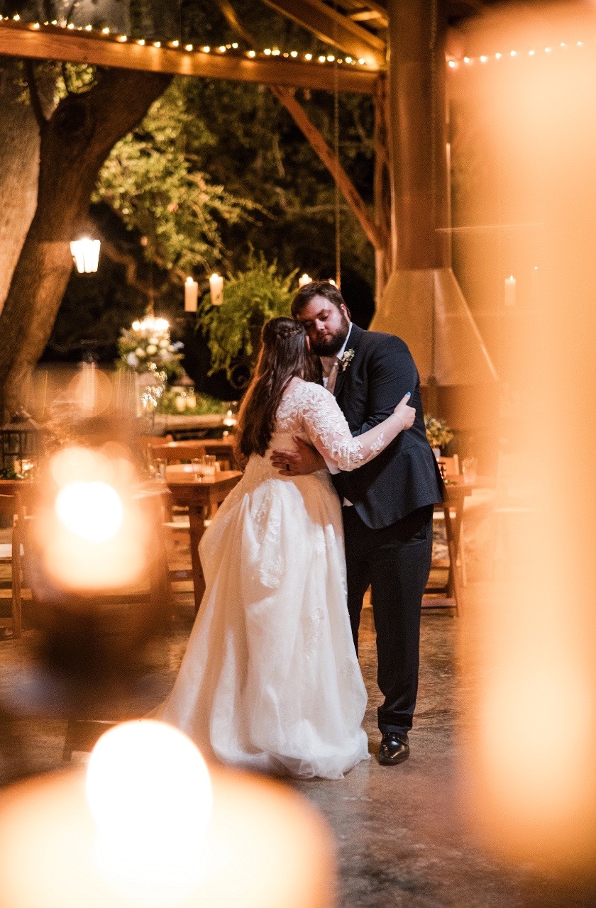 Newlyweds dancing together under lights at Old Glory Ranch Wimberley wedding venue
