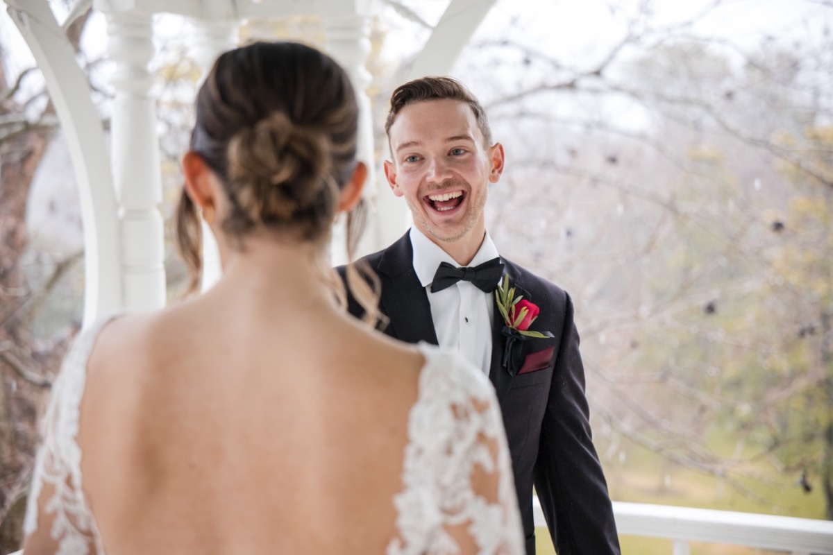 Groom adjusting boutonniere with groomsmen at Barr Mansion venue.