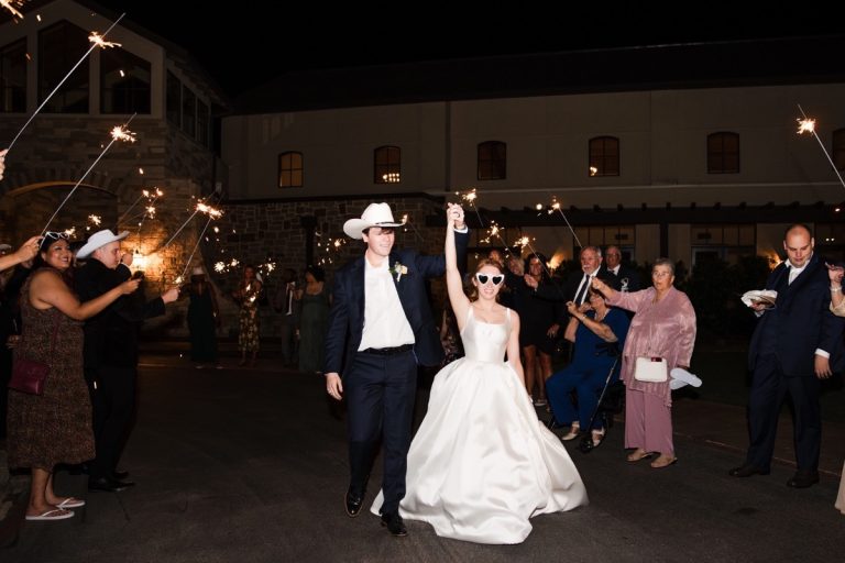 bride and groom exit from their wedding at Canyonwood Ridge. he is wearing a cowboy hat