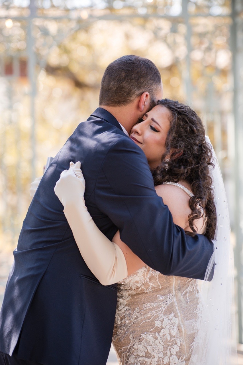 Bride's diamond earrings and wedding band sparkling in natural light at venue